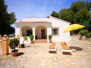 ein Haus mit zwei Liegestühlen und einem gelben Regenschirm in der Unterkunft Holiday Home Caleta in Jávea