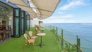 a balcony with tables and chairs and the ocean at Samcheok Peacehousing Spa Pet Pension in Samcheok