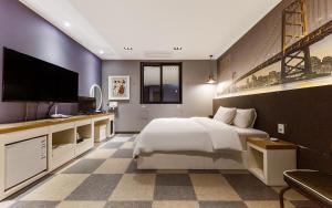 a bedroom with a large bed and a flat screen tv at Rings Hotel in Gunsan-si
