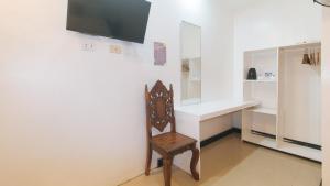 a chair in a room with a desk and a tv at RedDoorz @ Lualhati Garden Cottage El Nido Palawan in El Nido