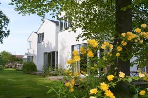 a white house with yellow flowers in the yard at Dahmerhof in Dahme