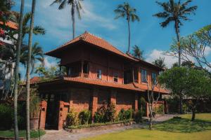 a house with palm trees in front of it at The ARIRAS Resort in Candidasa