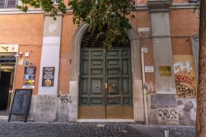 a large green door on a building with graffiti at Locanda San Cosimato in Rome