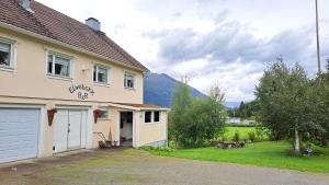 a house with a garage and a mountain in the background at Elvebakk Bed & Breakfast in Reed
