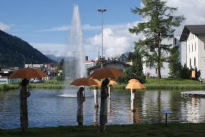 a group of people holding umbrellas in front of a fountain at Barga A2 Davos in Davos