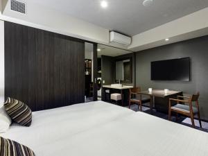 a hotel room with a bed and a desk and a tv at Tokyu Stay Hakata in Fukuoka