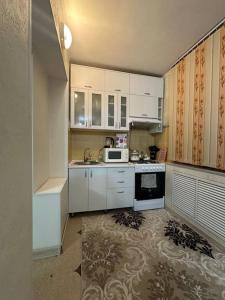 a small kitchen with white cabinets and a microwave at 3х комнатная по Толе би in Taraz