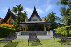 three chairs in the grass in front of a house at Villa Leo - Koh Chang in Trat
