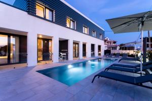 an outdoor swimming pool with chairs and an umbrella at Refúgio com Spa e Vista Mar - Ribamar Bluevillas in Ribamar