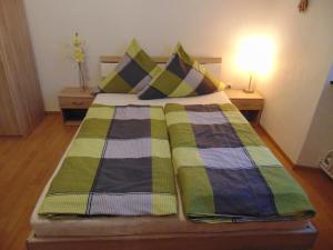 a bedroom with a bed with green and blue plaid sheets at Gasthaus Rebstock in Alken