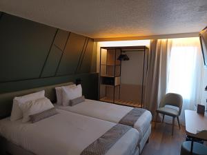 a hotel room with a bed and a chair at Hôtel Nell Axelle - Maison Tassoni in Saint-Marcel