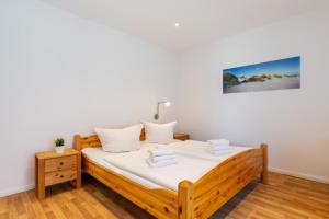 a bedroom with a wooden bed with white sheets at Ferienhaus Waldheide in Zempin