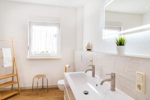 a white bathroom with a sink and a toilet at Ferienhaus Waldheide in Zempin +12 photos