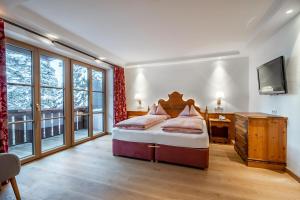 a bedroom with a bed and a desk and windows at Hotel Lech & Residenz Chesa Rosa in Lech am Arlberg