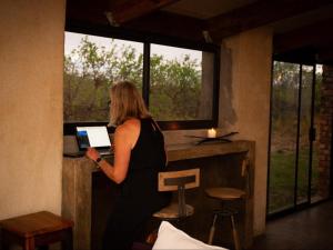 a woman standing at a bar with a laptop at Merwespont Guesthouses#DieHouthuis#Die Wyntenke#A Snoozer's Cottage# in Bonnievale