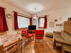 a living room with red chairs and a couch at Appartamento Al Ruscello in Canazei