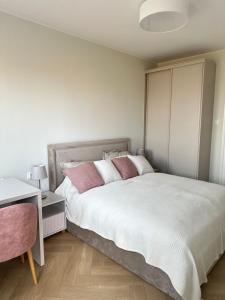 a bedroom with a large white bed with pink pillows at Apartament Premium Zamkowa A14 in Tczew