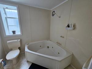 a white bathroom with a tub and a toilet at Private room in Wellington with views in Wellington