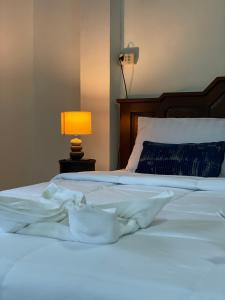 a bed with white sheets and a lamp on a table at Sunrise Beach Villa in Ban Bang Po