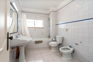 Un baño blanco con inodoro y lavabo. en Maralvor 001, en Alvor 12 fotos más