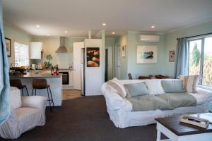 a living room with a white couch and a kitchen at Beach Front Wine makers cottage in Te Awanga