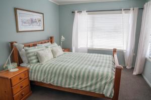 a bedroom with a bed with a striped bedspread and a window at Beach Front Wine makers cottage in Te Awanga