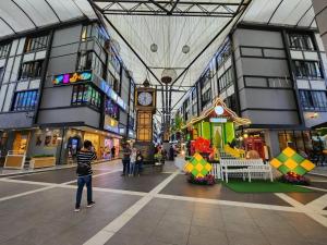 una persona in piedi in un centro commerciale con un orologio di TDOZE Hotel a Brinchang