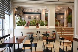 a restaurant with tables and chairs and a staircase at Hotel Achillion in Larisa