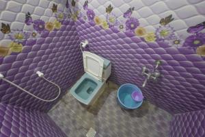 a purple bathroom with a toilet and flowers on the wall at Sai Guest House in Tiruvannāmalai +93 photos