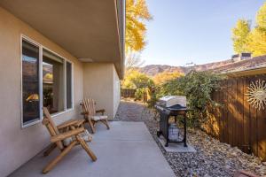 a patio with two wooden chairs and a grill at Cottonwoods 347 in Moab