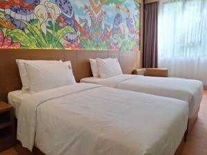 two beds in a hotel room with a painting on the wall at Alltrue Hotel Palangkaraya in Palangkaraya
