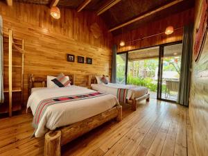 two beds in a room with wooden walls at Anne House Bac Ha in Bắc Hà