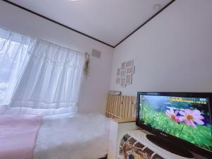 a bedroom with a bed and a flat screen tv at 樽前の雪 in Otaru