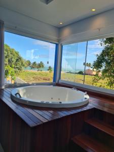a bath tub in a room with a large window at Hotel Paraiso Maragogi LTDA in Maragogi