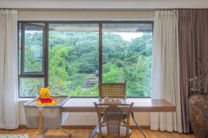 a stuffed winnie the pooh sitting on a table in front of a window at Return to Emei Hotel in Baoguosi