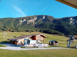 a house in a field with mountains in the background at Terrasses D 306 PARC NAT VANOISE appart 6 pers in Val Cenis +7 photos
