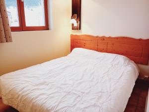 a bedroom with a white bed with a wooden headboard at Terrasses E 309 PARC NAT VANOISE appart 6 pers in Val Cenis