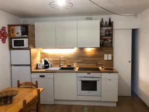 a kitchen with white cabinets and a sink and a table at Appartement T2 Ste Marie de Campan - La Mongie - Tourmalet in Campan