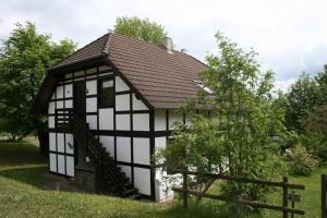 ein kleines weißes und schwarzes Gebäude auf einem Feld in der Unterkunft Am Sternberg 227 in Frankenau