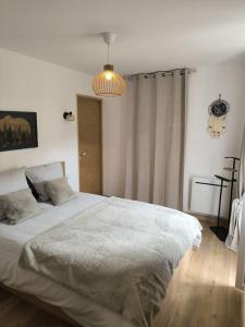 a bedroom with a large white bed with a chandelier at Sublime 3 p au centre-ville in Saint-Martin-Vésubie