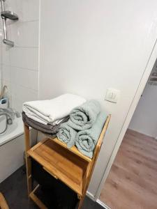 a pile of towels sitting on a stool in a bathroom at Chic & Spacieux-Paris à porte-Au pied du Métro 14 in Saint-Ouen +7 photos