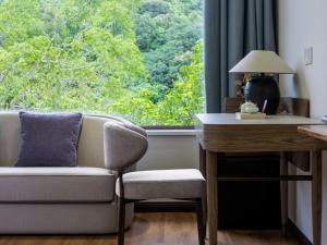 a living room with a couch and a desk and a window at Return to Emei Hotel in Baoguosi