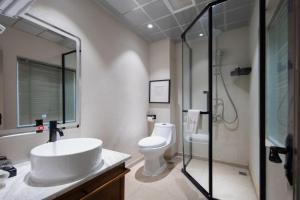 a bathroom with a sink and a toilet and a shower at Return to Emei Hotel in Baoguosi