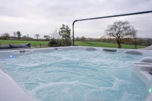 a jacuzzi tub with a view of a golf course at Grange House - Sleeps 24 in Alvechurch