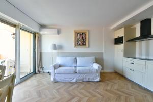salon z białą kanapą i kuchnią w obiekcie L'ALIZEE avec jolie terrasse vue sur la ville, charmant studio dans le centre de Cannes w Cannes