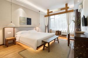 a bedroom with a white bed and a large window at Return to Emei Hotel in Baoguosi
