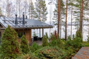 a house with a wooden deck in the woods at Luxury guesthouse, beachfront sauna in Jyväskylä