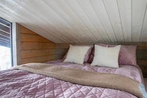 a bed in a room with a wooden ceiling at Luxury guesthouse, beachfront sauna in Jyväskylä