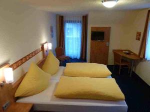 ein Hotelzimmer mit 2 Betten und gelben Kissen in der Unterkunft Hotel Schützen in Bad Peterstal-Griesbach