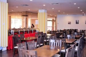 ein leeres Restaurant mit Tischen und Stühlen und eine Frau in der Unterkunft La Boss Hotel in Malakka